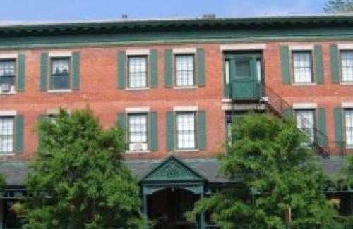 Red brick building, green paneling, blue skies, two small trees in front